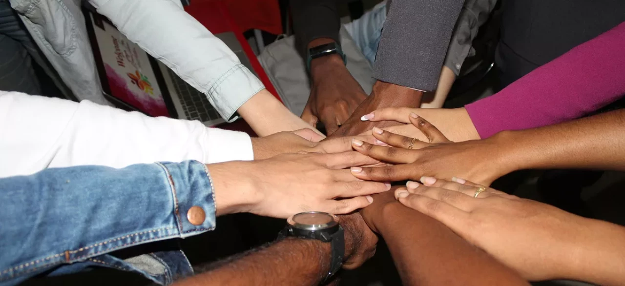 Diverse group of people placing their hands together in a team huddle